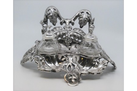 Tinteiro em prata com folhas de acanto relevadas, dois depósitos em vidro e assente sobre três pés recortados.